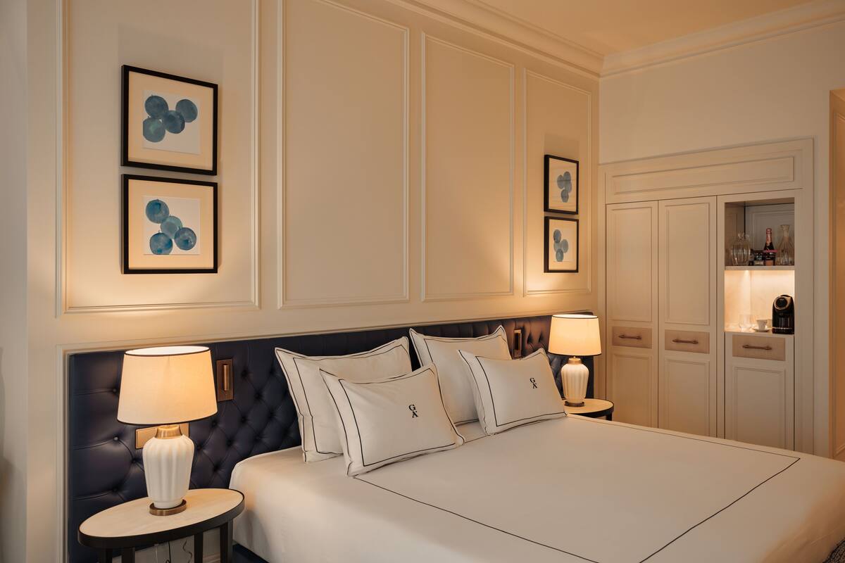 A hotel room with a large bed, two bedside tables, a dark headboard, and framed artwork on the wall.