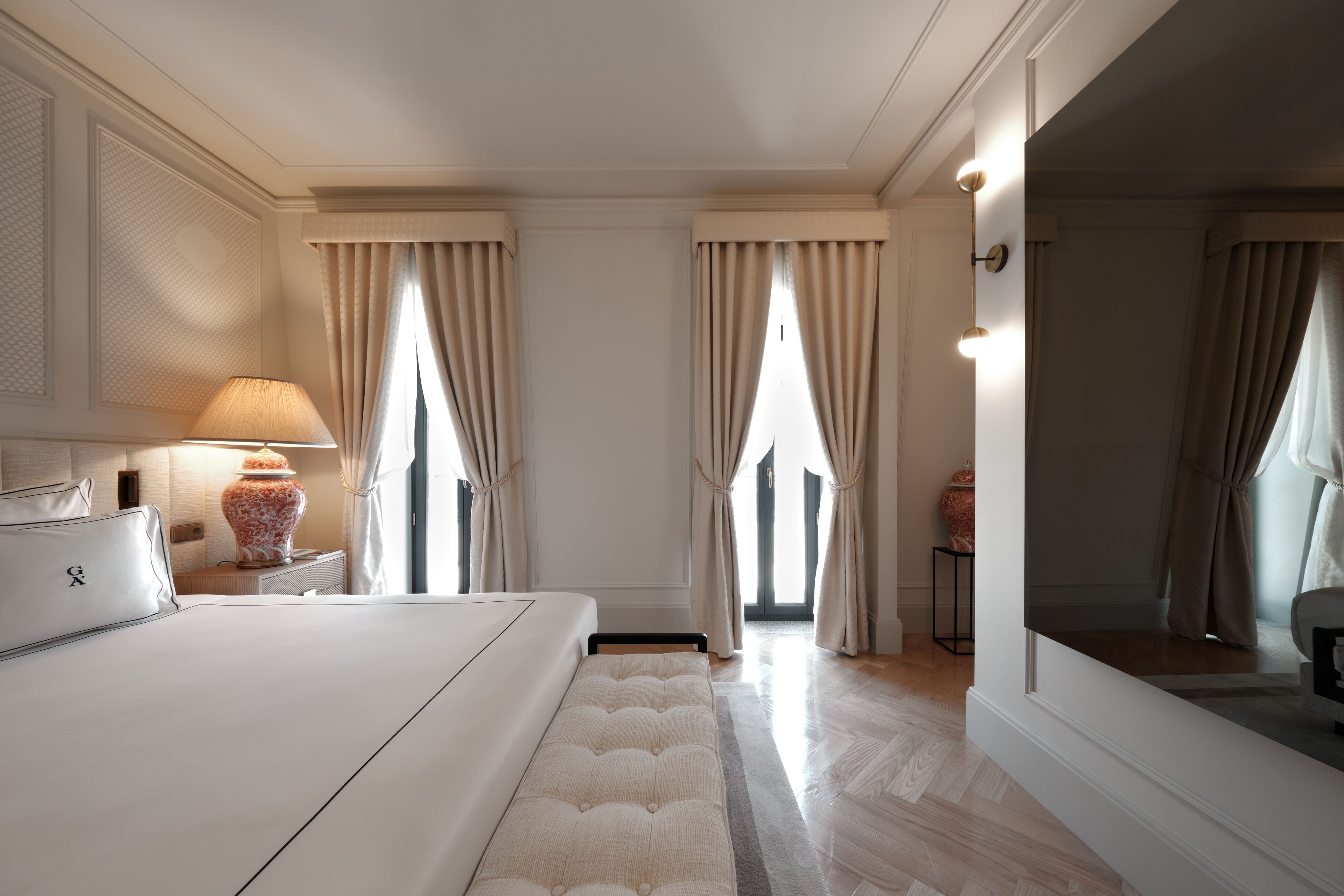 Una habitación de hotel con una cama grande, una mesita de noche con lámpara y un espejo.