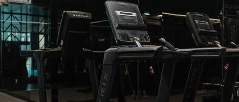 A gym with treadmills and weight machines, featuring a modern design with geometric lighting.