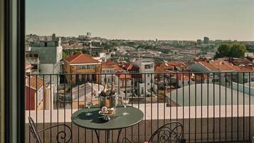 A balcony with a table and chairs, overlooking a cityscape with buildings and a clear sky.