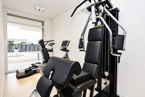 A gym with exercise equipment, a treadmill, and a stationary bike. - Opalia Residence - Eva's Elegance (Peschiera del Garda)