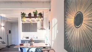 A modern living room with a large wall-mounted artwork, a sofa, and a dining area in the background. - Langhe Wine & Relax (Piemonte)