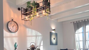 A modern living room with a dining area, featuring a wooden dining table, light blue chairs, a sofa with cushions, and a blue ottoman. - Langhe Wine & Relax (Piemonte)