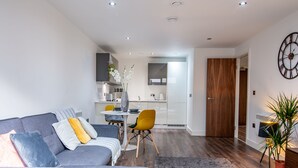 A modern living room with a grey sofa, a yellow chair, and a dining area with a white table and chairs. - Impressive Apartment in Birmingham (Birmingham)