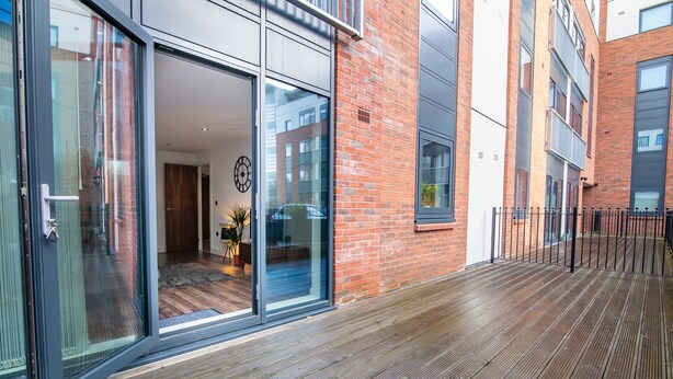 A modern building with large glass doors, a wooden deck, and a brick facade. - Impressive Apartment in Birmingham (Birmingham)