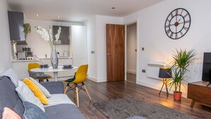 A modern living room with a grey sofa, yellow chair, and a dining area with a table and chairs. - Impressive Apartment in Birmingham (Birmingham)