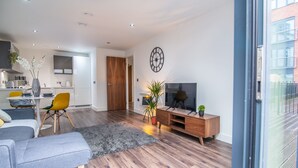 A modern living room with a grey sofa, yellow chairs, a wooden entertainment unit, and a TV. - Impressive Apartment in Birmingham (Birmingham)