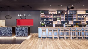 A modern bar area with a red counter and multiple shelves displaying bottles and glasses. - IntercityHotel Karlsruhe (Karlsruhe)