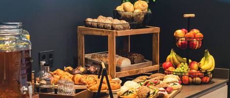 A buffet with various food items and a fruit basket.