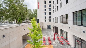 A courtyard with outdoor seating, a tree, and a building with a sign reading "Intercity Hotel". - IntercityHotel Karlsruhe (Karlsruhe)