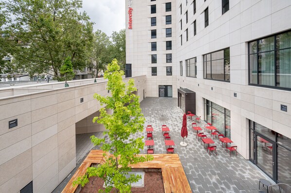A courtyard with outdoor seating, a tree, and a building with a sign reading "Intercity Hotel". - IntercityHotel Karlsruhe (Karlsruhe)