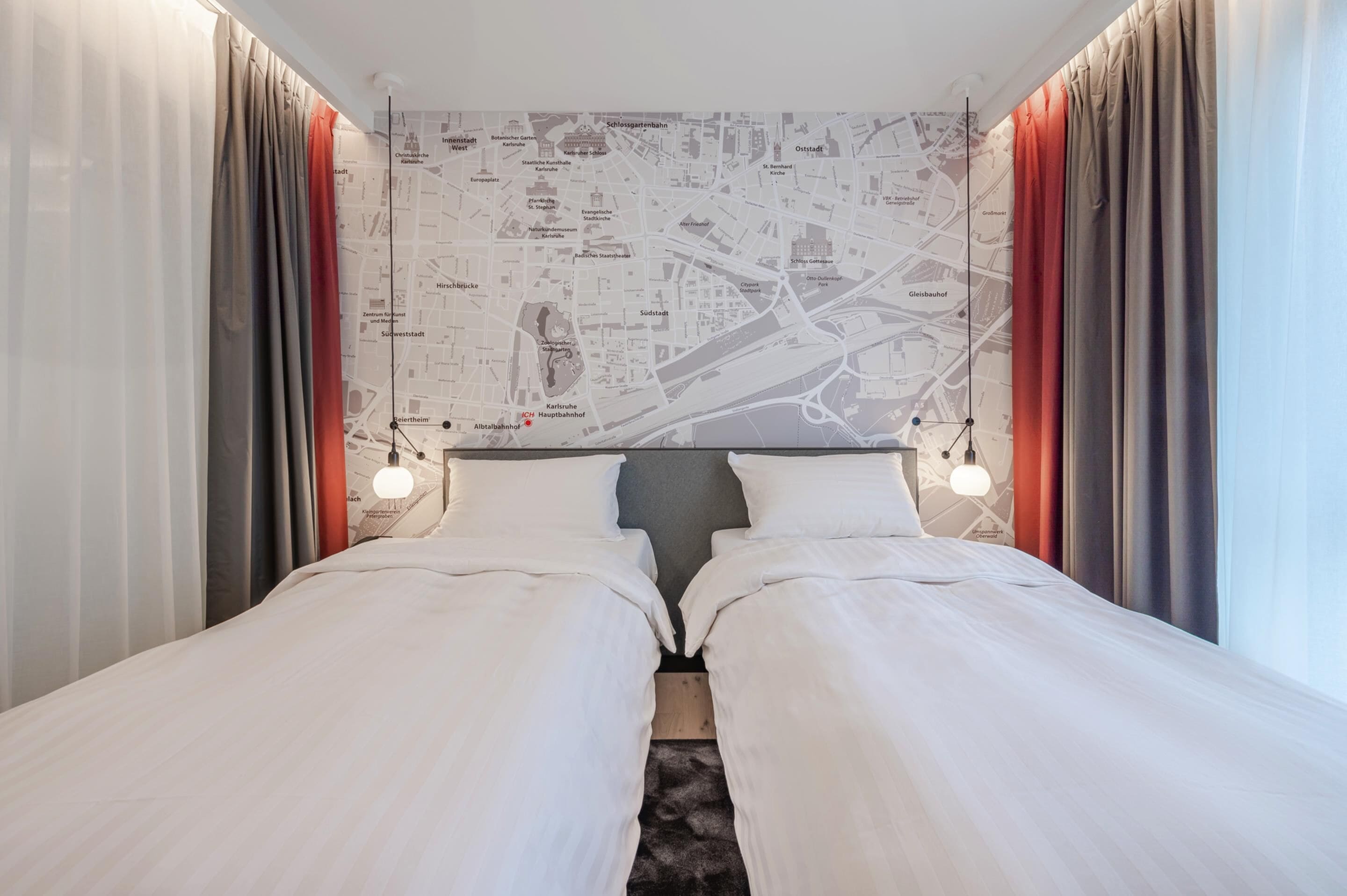 Une chambre d’hôtel avec un grand lit, deux tables de chevet, une carte accrochée au mur et des rideaux aux fenêtres.