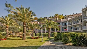 Hotel amb diverses plantes, palmeres a l'exterior i un jardí ben cuidat amb un camí de pedra.
