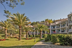 A hotel with multiple floors, outdoor palm trees, and a well-maintained garden with a stone pathway.