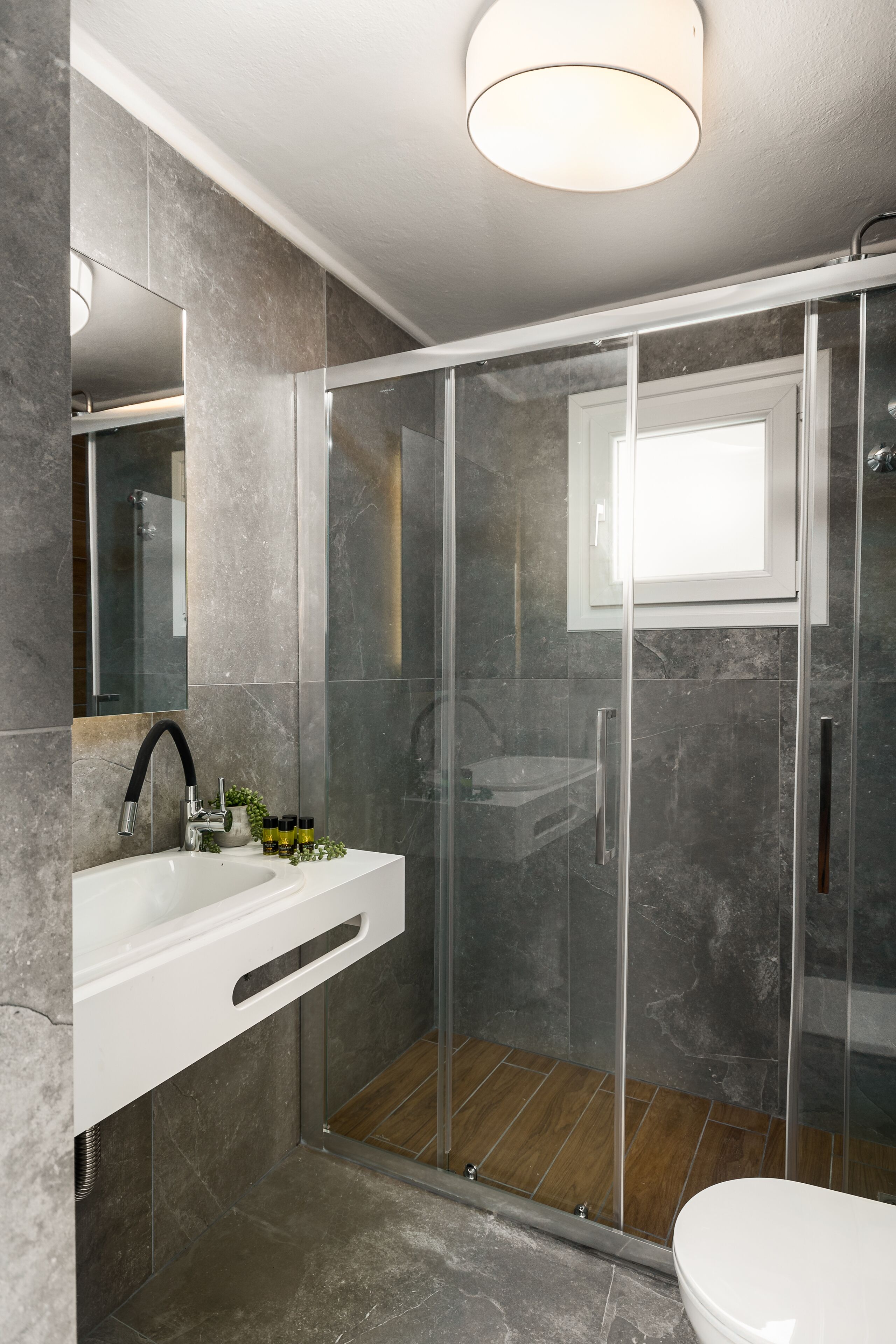 A modern bathroom with a glass shower enclosure, a white sink, and a large mirror.