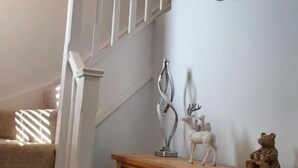 Una escalera con un aparador de madera y objetos decorativos, incluyendo una cabeza de ciervo y una figura de oso.