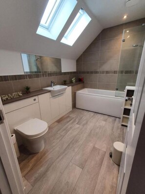Ein modernes Badezimmer mit Oberlicht, einer Badewanne, einer Toilette und einem Waschbecken.