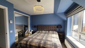 Un dormitorio con una cama grande, un espejo, un aparador y una ventana con cortinas.