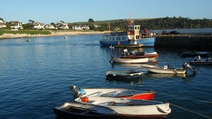 A harbor with various boats docked, a lighthouse, and houses in the background. - Crows Nest: a modern apartment in the centre of St Mawes with stunning sea views (St Mawes)