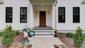 A two-story house with a front porch, a wooden door, and two black-framed windows on each side. - Bellview Cottage - MOUNTAIN HOUSE VACATION RENTAL (Hot Springs)