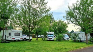 A campsite with RVs parked among trees, a picnic table, and a playground. - Electrified Camping Pitch (Bessé-sur-Braye)
