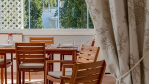 Een houten eettafel met stoelen, een glazen pitcher en een servies.