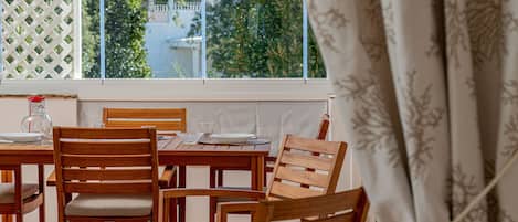 A wooden dining table with chairs, a glass pitcher, and a plate set.