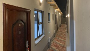 Un pasillo con puerta de madera, ventanas y suelo de ladrillo.