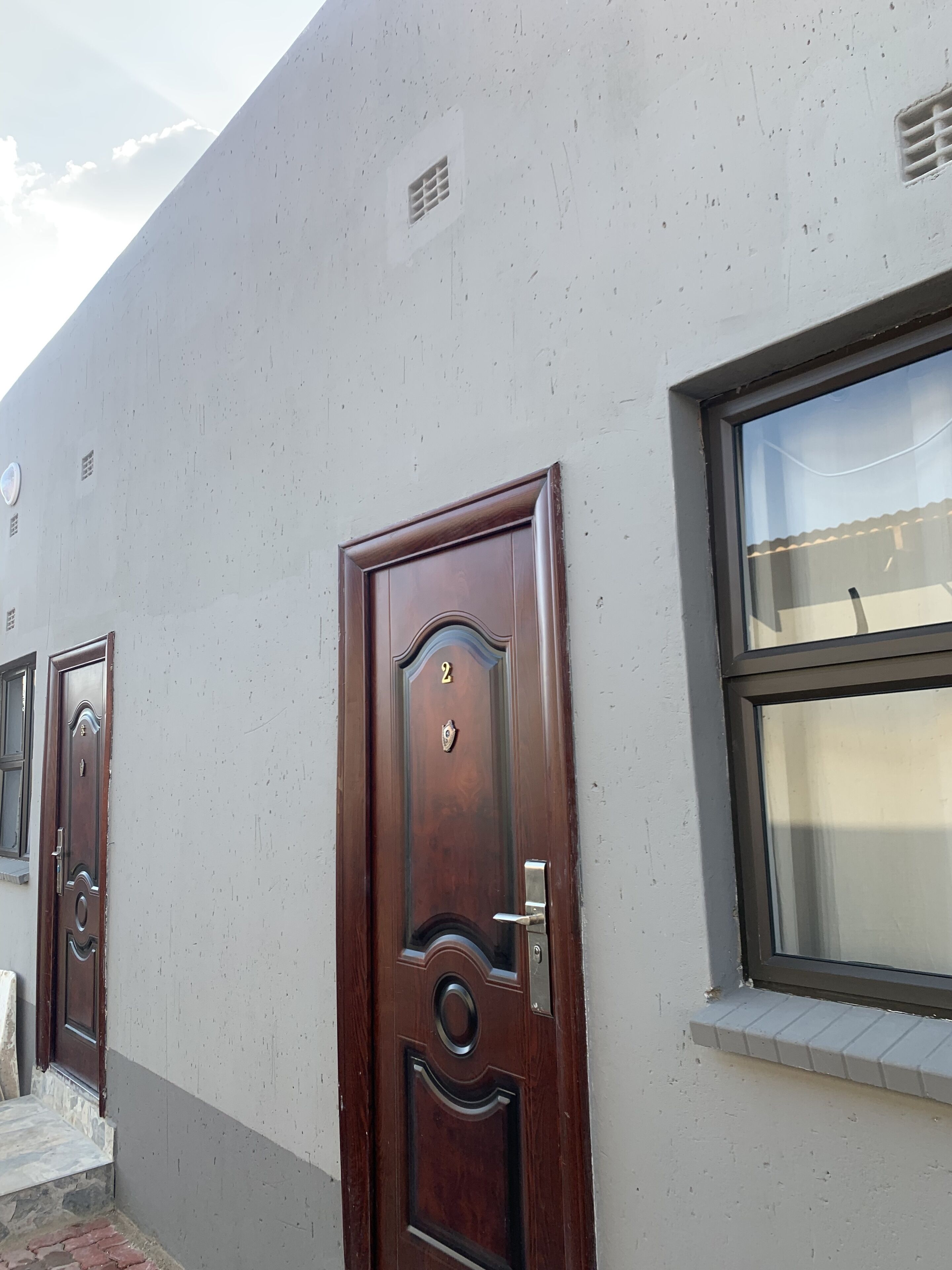 Ein Gebäude mit einem großen Fenster und einer Holztür, auf der die Zahl 2 angebracht ist.