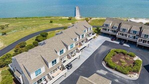 A coastal residential area with multiple two-story houses, a central road, and a lighthouse in the background. - Vacation Rental in the Bayfront Community of Port Lewes (Lewes Beach)