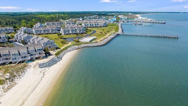 A coastal residential area with houses along a sandy beach and a pier extending into the water. - Vacation Rental in the Bayfront Community of Port Lewes (Lewes Beach)