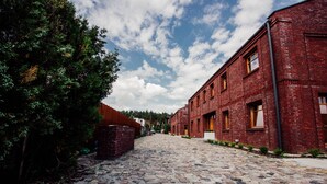 Una calle empedrada flanqueada por edificios de ladrillo rojo, una valla de madera y abundante vegetación.