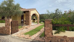 A stone-walled house with a paved entrance and a small patio. - Villa Patrizia (Castiadas)