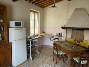 A compact kitchen with a microwave, refrigerator, and a small dining table with chairs.