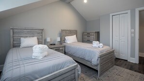 A bedroom with two beds, a ceiling light, and a door.