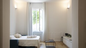 A bedroom with a bed, bedside tables, a window with curtains, a radiator, and a small desk with a chair. - Sinonda Luxury Apartment (Maiori)