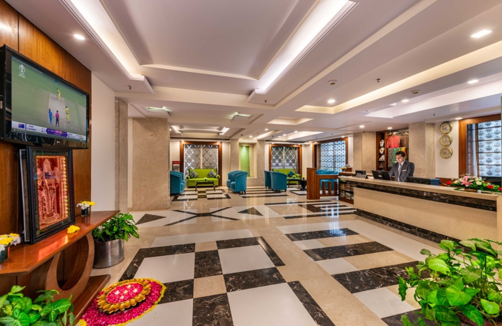 Un vestíbulo de hotel con una recepción, una zona de estar y un televisor mostrando un evento deportivo.