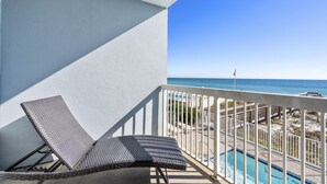 Ein Balkon mit weißer Reling, einem Korbsessel und Blick aufs Meer.