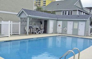 Une piscine dotée d’une zone abritée, d’un poste de surveillance pour les sauveteurs et d’une clôture blanche.