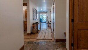Un couloir avec un plancher en bois, un tapis et une porte sur le côté droit.