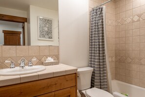 A bathroom with a sink, mirror, toilet, and shower curtain. - Westridge Condo 26 - Walk to Bald Mountain Lifts 3BR with AC (Ketchum)