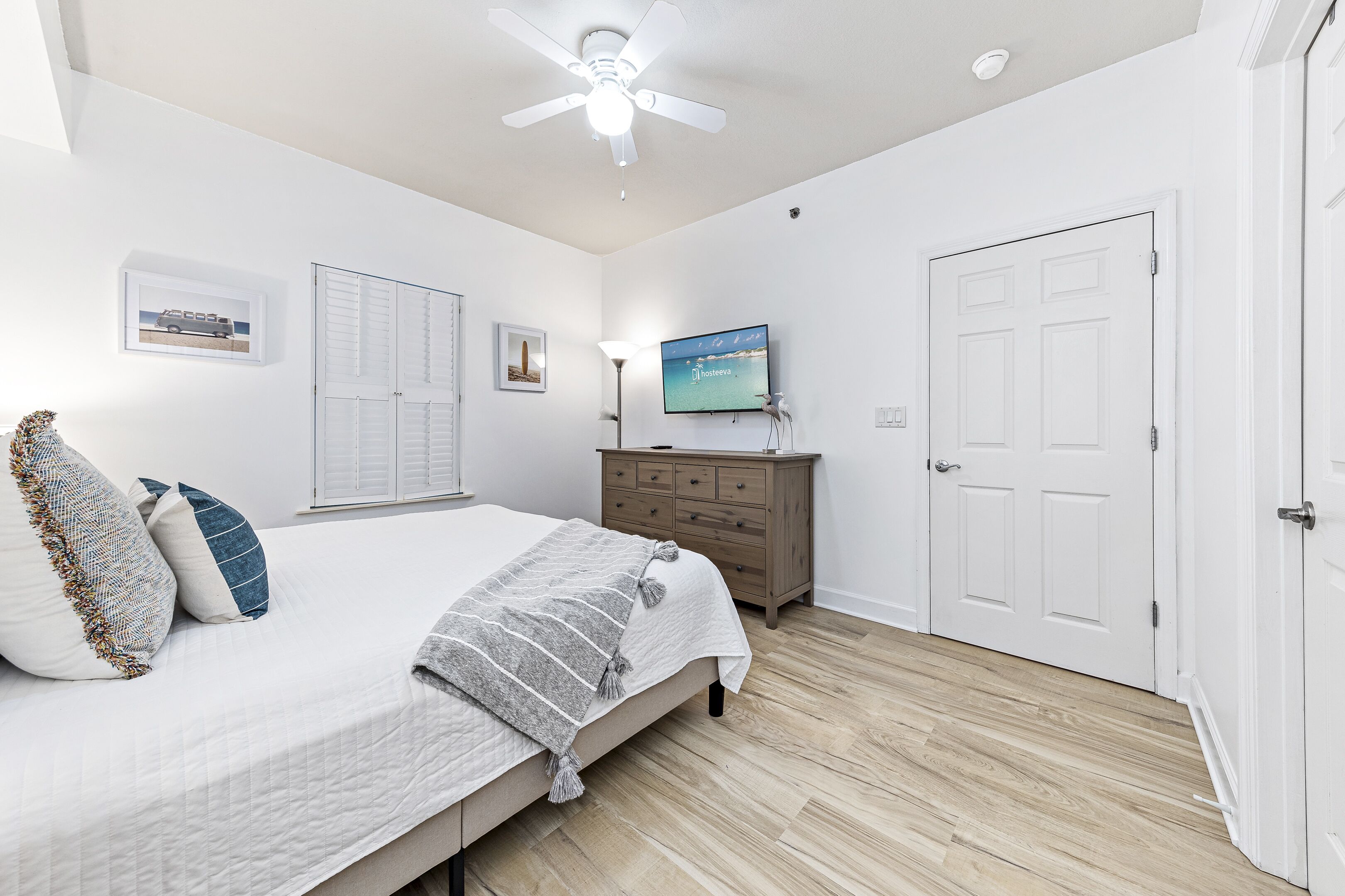 Un dormitorio con cama, cómoda, televisor y puerta.