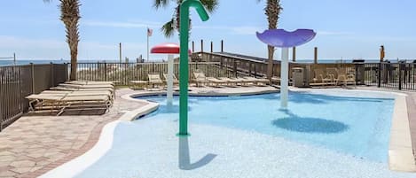A pool area with lounge chairs, a palm tree, and a fence.