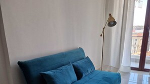 A blue sofa in a room with a tiled floor and a floor lamp. - Art Flat Municipio (Naples)