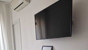 A modern room with a mounted TV, a framed picture on a floating shelf, and a door. - Art Flat Municipio (Naples)