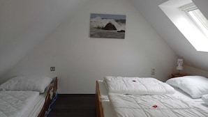 A small, dimly lit room with two beds, a painting on the wall, and a skylight. - Vacation apartment with dog in Cuxhaven Sahlenburg Apartment 3 (Cuxhaven)