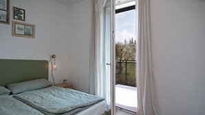 Une chambre à coucher avec un lit, une table de chevet avec une lampe, et une vue sur l’extérieur grâce à une porte coulissante.