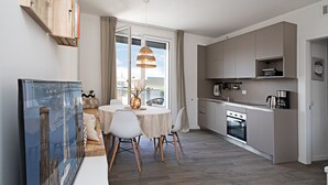 Une cuisine moderne dotée d’appareils électroménagers intégrés, un coin repas avec une table ronde et des chaises, et une grande fenêtre offrant une vue dégagée.