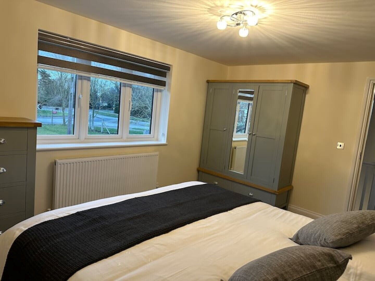 A bedroom with a bed, a wardrobe, a window, and a radiator.