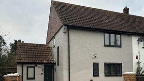 A two-story house with a driveway leading to a gated entrance. - The Grey Retreat (Shepperton)